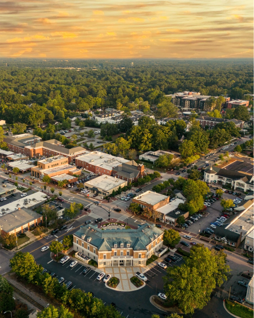 Aerial view of a small city or suburban downtown area surrounded by trees at sunset