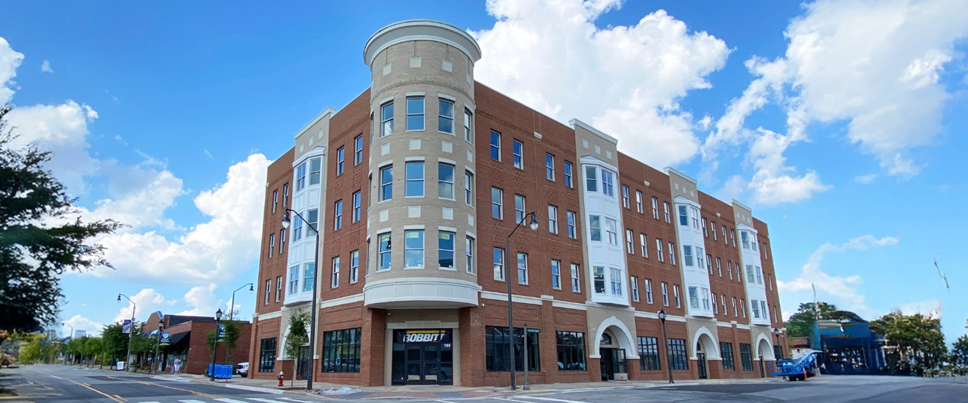 Four-story red brick building with retail space on the ground floor and apartments or offices above