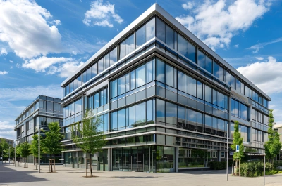 Modern glass office building under a bright blue sky