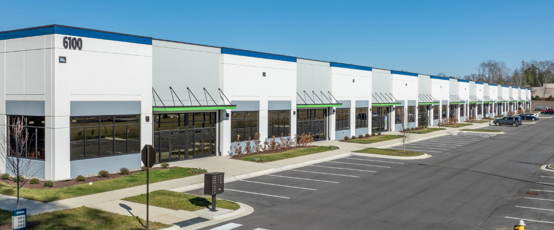 Modern industrial or business park building with multiple units and a large parking lot