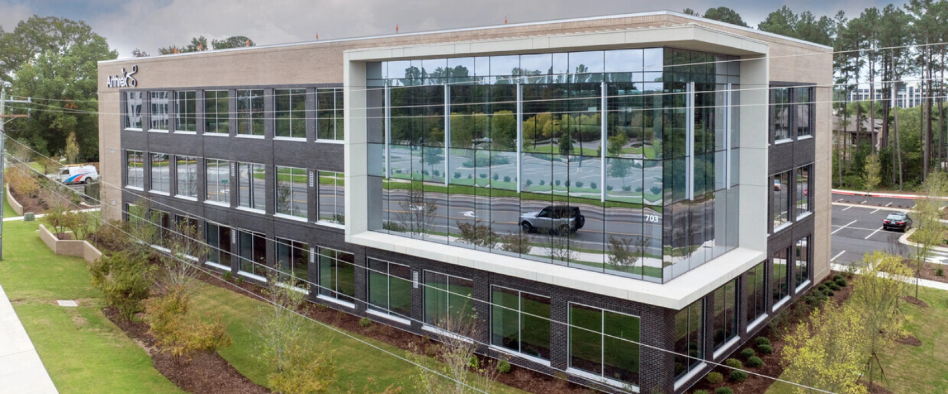 Modern three-story office building with large reflective glass windows and landscaped surroundings
