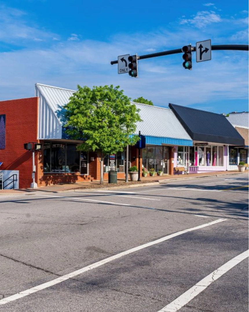 Small-town street with colorful storefronts and a traffic light at the intersection
